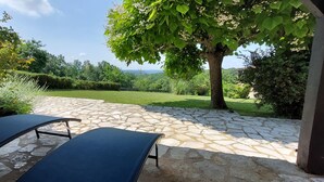 A patio area with stone flooring and two lounge chairs. - Le Bellevue, quiet gite with panoramic view 10 minutes from Sarlat (Vezac)