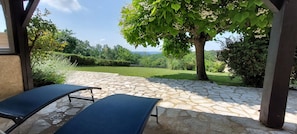 A patio area with stone flooring and two lounge chairs. - Le Bellevue, quiet gite with panoramic view 10 minutes from Sarlat (Vezac)