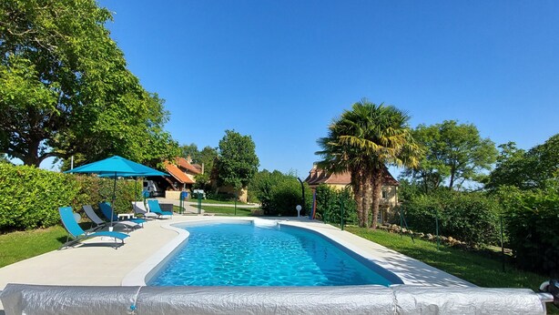 A swimming pool with lounge chairs and a covered area, surrounded by greenery and trees. - Le Bellevue, quiet gite with panoramic view 10 minutes from Sarlat (Vezac)
