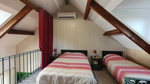A bedroom with two beds, a red curtain, an air conditioner, and a balcony with a railing.