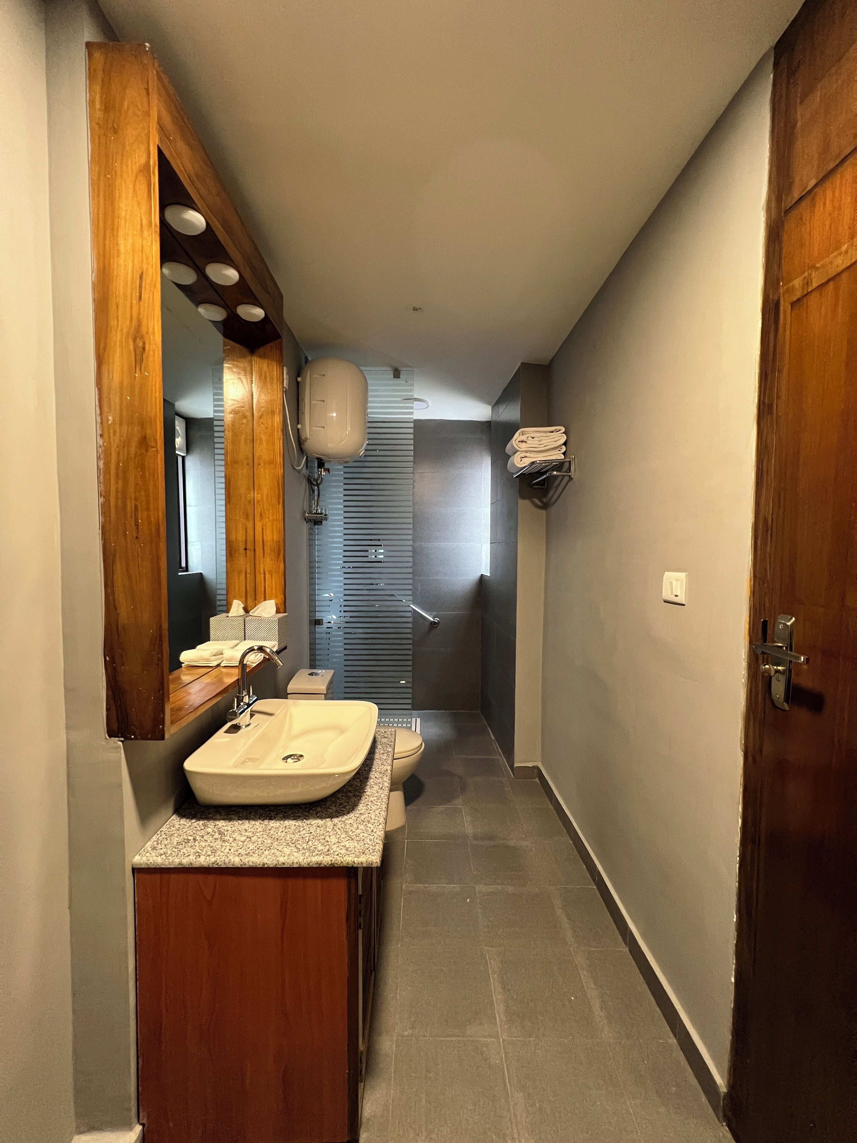 Une salle de bain moderne avec un meuble-lavabo en bois, un grand miroir et un espace douche.
