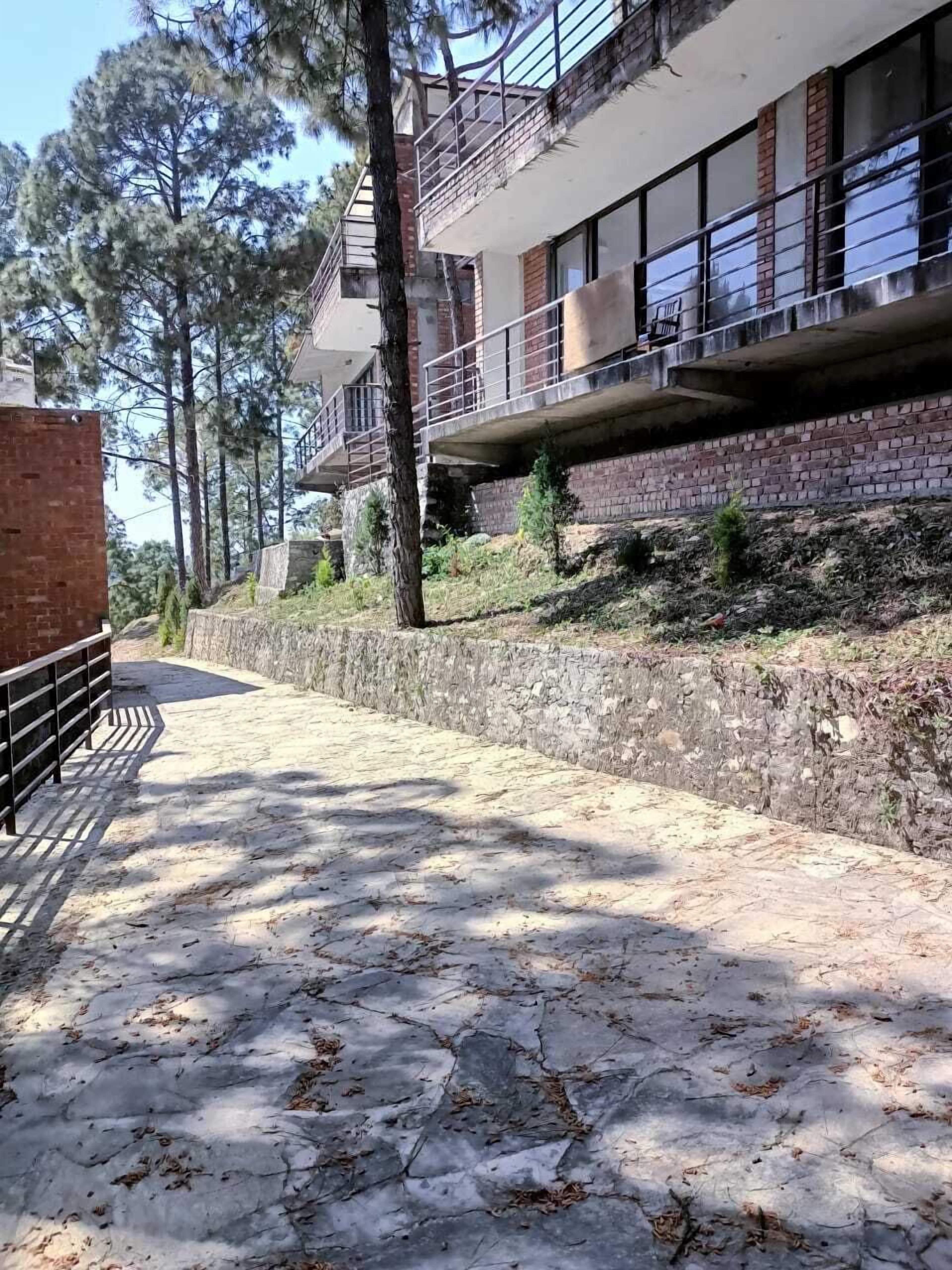 Un sendero que conduce a un edificio con un muro de piedra y una barandilla de metal.