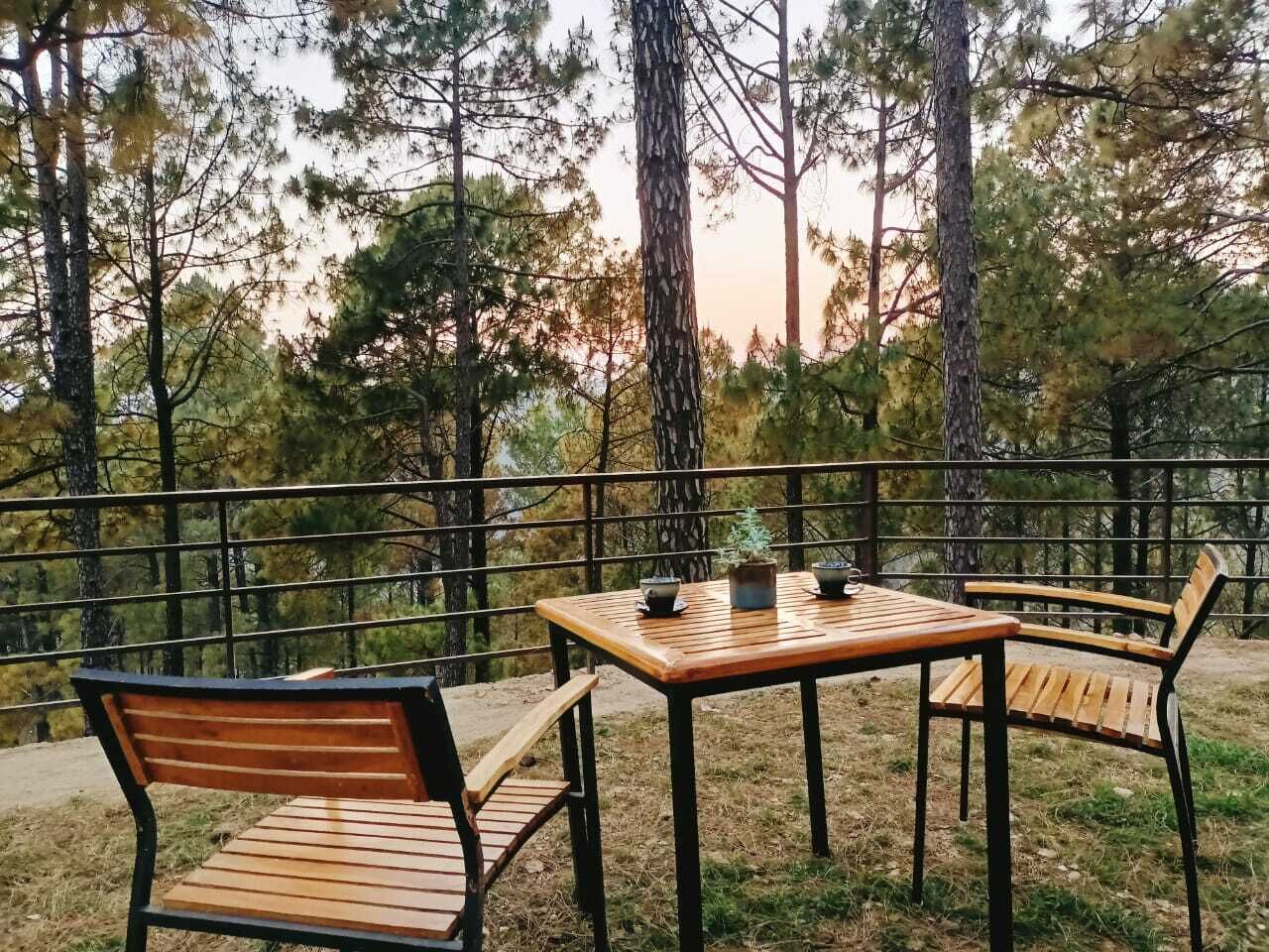 An outdoor seating area with a table and two chairs, surrounded by a metal railing.