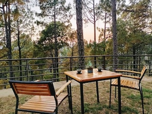 An outdoor seating area with a table and two chairs, surrounded by a metal railing. - BluSalzz Escapade, Lansdowne - Uttarakhand (Lansdowne)