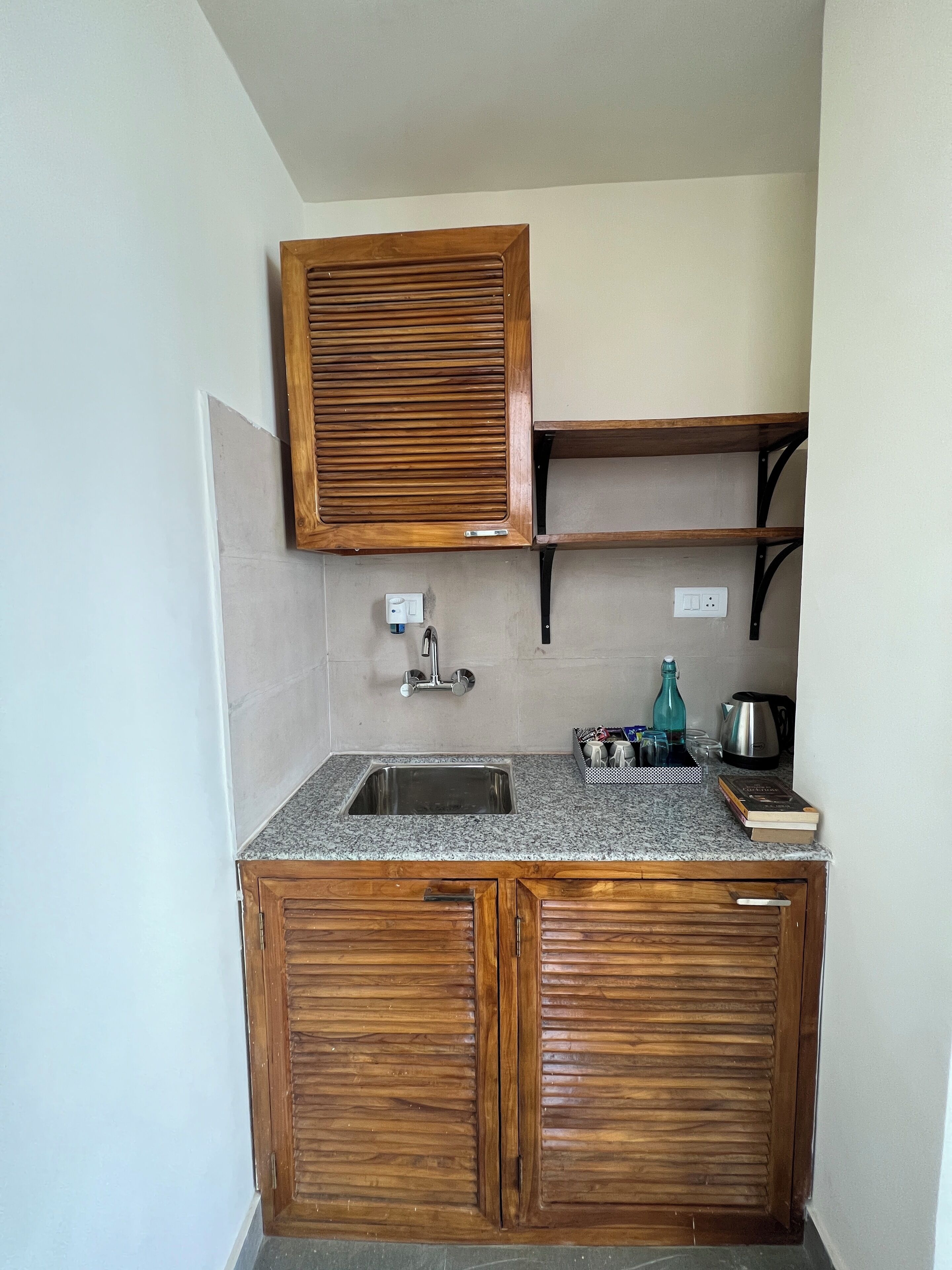 A kitchen with wooden cabinets, a granite countertop, a built-in sink, and a shelf above the countertop.