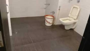 A small bathroom with a toilet and a bucket.