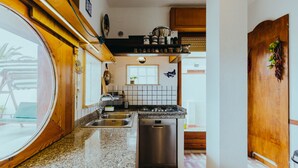 A kitchen with a granite countertop, stainless steel appliances, and a wooden door. - Heart of Ognina - Veliero - Apartment with sea view (Ognina)