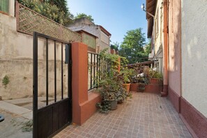 A narrow alleyway with a gated entrance, potted plants, and a tiled floor. - Montello Sweet House Holiday Home in Cagliari – Central, Well-Connected, and Comfortable (Cagliari)
