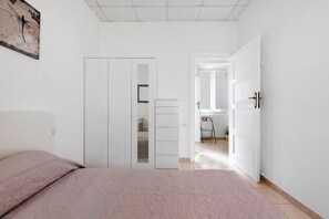 A bedroom with a bed, a wardrobe, and a door leading to another room. - Montello Sweet House Holiday Home in Cagliari – Central, Well-Connected, and Comfortable (Cagliari)