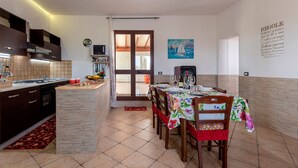 A kitchen with a dining area, a TV, and a painting on the wall. - Villa "Casa Vacanza Errante" with Sea View, Pool & Wi-Fi (menfi)