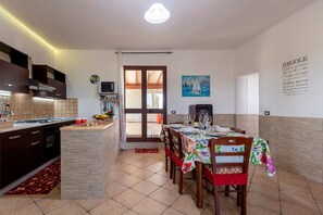 A kitchen with a dining area, a TV, and a painting on the wall.