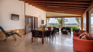 A spacious living area with a dining table, chairs, a sofa, and a TV mounted on the wall. - Villa "Casa Vacanza Errante" with Sea View, Pool & Wi-Fi (menfi)