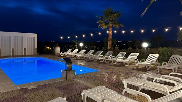 A swimming pool with lounge chairs and string lights. - Villa "Casa Vacanza Errante" with Sea View, Pool & Wi-Fi (menfi)