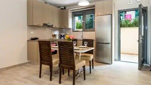 A modern kitchen with a dining area, featuring light wooden cabinets, a stainless steel refrigerator, and a window providing natural light. - Casa De' Fiori Kefalonia★Family Retreat (Σκάλα)