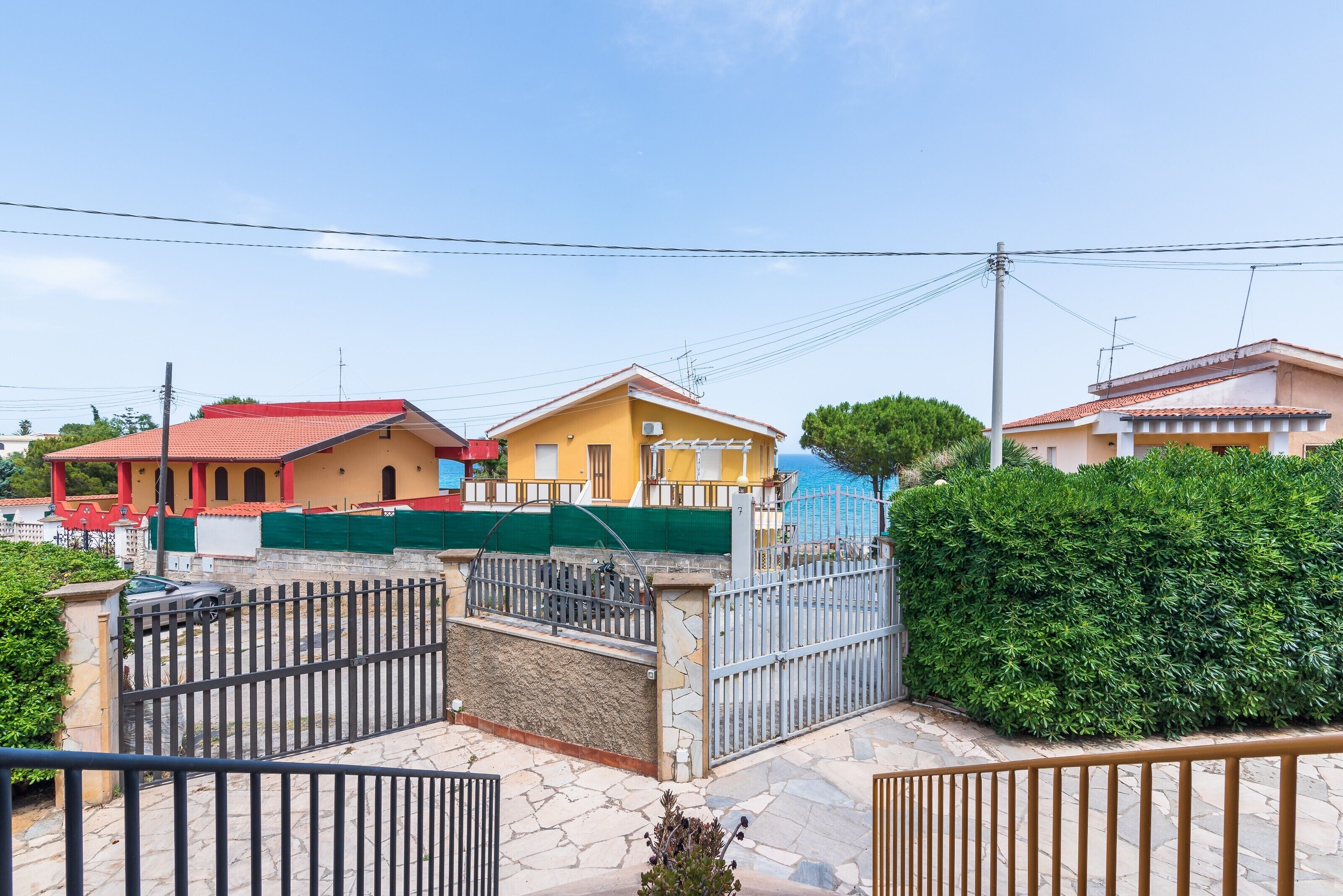 A residential area with houses, a gated entrance, and a clear sky.