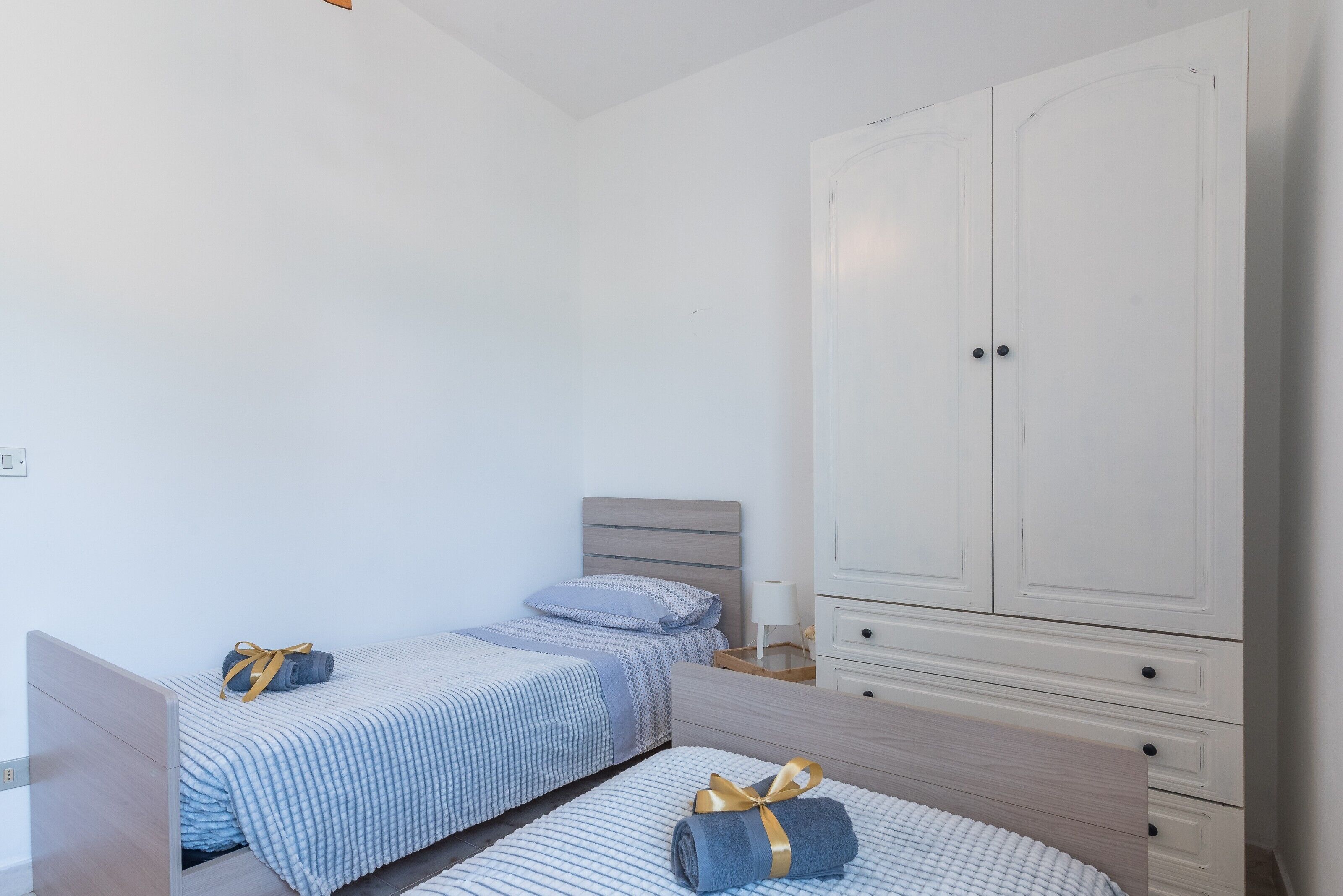 Une chambre avec deux lits, une armoire et une table de chevet.