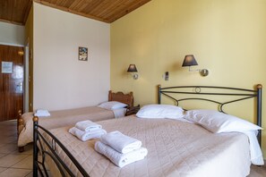 Hotellihuone, jossa on kaksi sänkyä, puiset päätylevyt, seinään kiinnitetyt lamput ja siististi taitetut pyyhkeet.