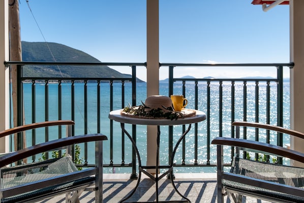 A balcony with a table, chairs, and a view of the sea.