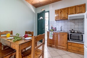 A kitchen with wooden cabinets, a dining table with chairs, a microwave, and a tiled backsplash.
