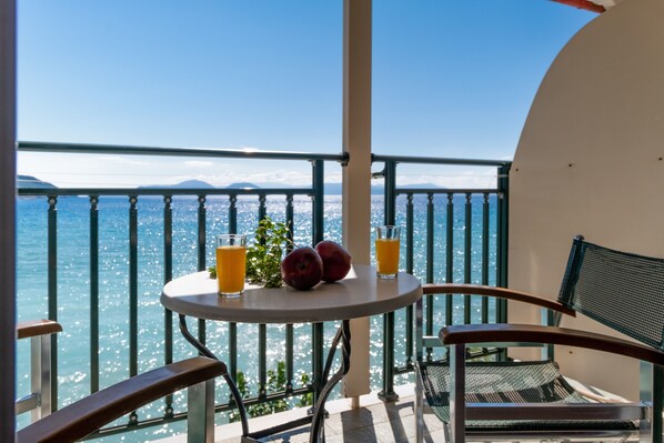 Un balcon avec une table, deux chaises et une vue sur la mer.