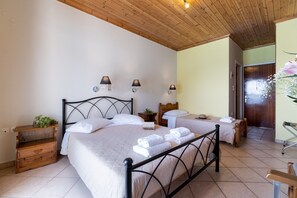 A bedroom with a bed, bedside tables, a nightstand, a wooden headboard, wall-mounted lamps, and a door.