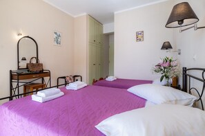 Une chambre d’hôtel avec deux lits, une table de chevet en bois, un miroir, une lampe et une étagère fixée au mur.
