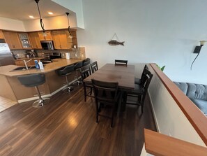 Una cocina moderna con armarios de madera, un refrigerador de acero inoxidable y una barra con taburetes.