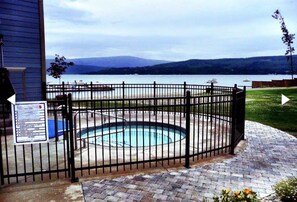 Zona de piscina con valla, señalización y vista a un lago y montañas.