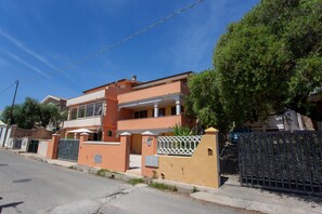 Ein zweistöckiges Wohngebäude mit geschlossenem Eingangsbereich, einem Balkon und einem Baum davor.