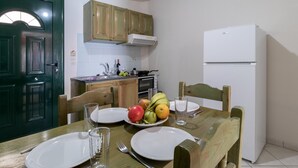 A dining table with plates, cutlery, and a glass of water. There is a refrigerator and wooden cabinets in the background. - Holiday Apartment 'Apostolos Apartment 2' Close to Beach with Sea View (Lefkada)