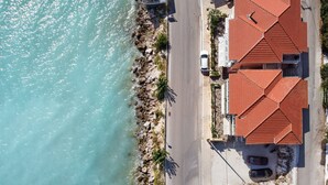 An aerial view of a coastal property with a road leading to a building with red-tiled roofs, adjacent to a rocky shoreline. - Holiday Apartment 'Apostolos Apartment 2' Close to Beach with Sea View (Lefkada)