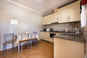 Une cuisine équipée d’une table à manger, de chaises, de placards, d’une cuisinière et d’un évier.