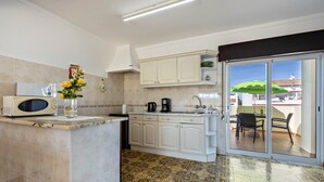 A kitchen with a microwave, coffee maker, and a vase of flowers. - Holiday Home Villas Brites nº5 with Open Terrace, Shared Pool & Wi-Fi (Burgau)