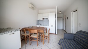 Een ruimtelijk ingerichte leefruimte met kitchenette, eethoek en een zithoek.