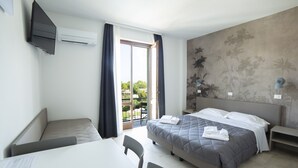 A hotel room with a bed, a desk, a chair, a TV, and a balcony with a view. - Junior Suite 2 with Shared Pool & Balcony (Manerba del Garda)