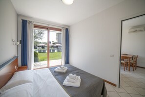 A hotel room with a bed, a small table, and a view of the outdoor area.