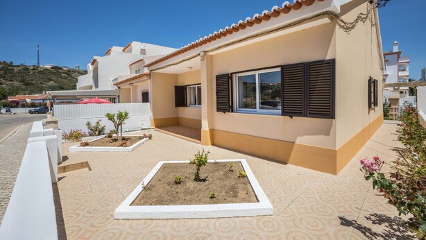 A modern house with a tiled patio, a small garden, and a clear blue sky. - Holiday Home Casa Fernandes with Shared Pool, Open Terrace & Wi-Fi (Burgau)