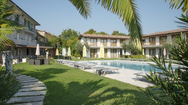 A hotel with a pool, outdoor seating, and a well-maintained garden. - Residence Molino Trilocale 12 (Manerba del Garda)