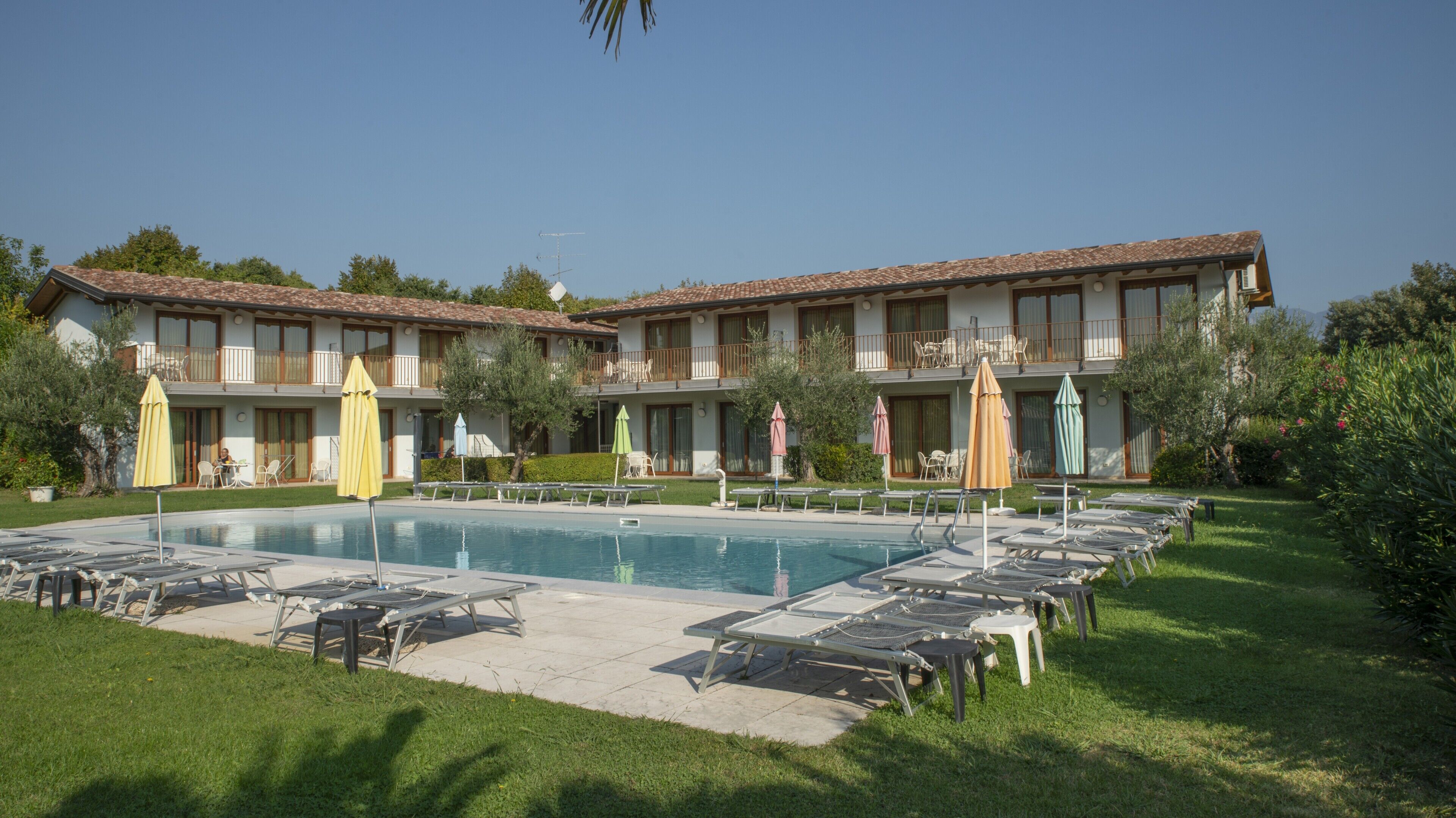 A hotel with a swimming pool, multiple balconies, and outdoor seating areas.