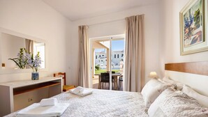 Ein Hotelzimmer mit Bett, Schreibtisch, Stuhl, einem Fenster mit Vorhängen und einem Bild an der Wand.