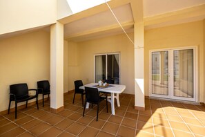 A balcony with a table, chairs, and a sliding glass door.