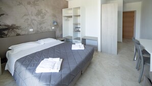 A modern hotel room with a bed, a desk, and a wardrobe. - Junior Suite 5 with Shared Pool and Private Balcony (Manerba del Garda)