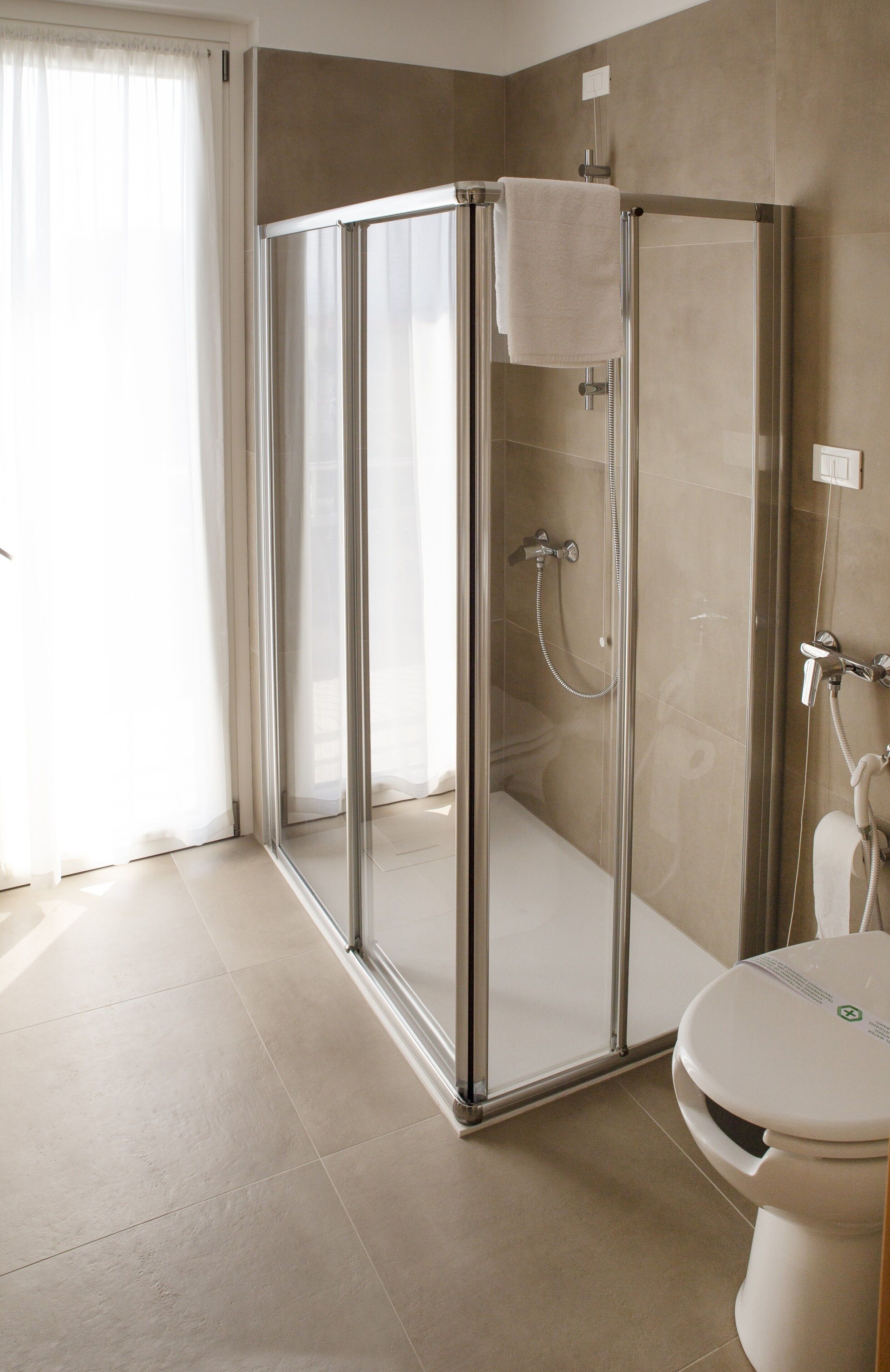 A modern bathroom with a glass-enclosed shower, a toilet, and a sink.