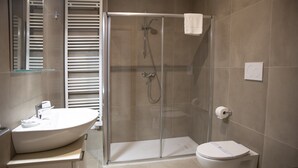 Un bany modern amb dutxa de vidre, vàter i bidé.