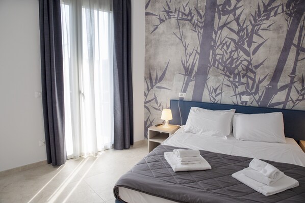 A hotel room with a bed, a nightstand, a lamp, and a wall with a bamboo pattern.