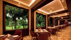 Un restaurante con un amplio comedor, grandes ventanales que dan a zonas verdes e iluminación moderna.