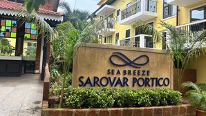 Señal de 'Sea Breeze Sarovar Portico' con un edificio moderno al fondo.