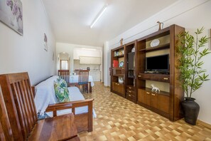Quarto com cama, móveis de madeira, televisão e estante de livros.