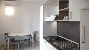A modern kitchen with a black countertop, stainless steel sink, and white cabinets. There is a dining table with four chairs. - Suite 2 with Shared Pool and Private Balcony (Manerba del Garda)