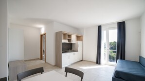 A modern apartment with a kitchenette, a dining area, a sofa, and a balcony with curtains. - Deluxe Suite 1 with Shared Pool and Private Balcony (Manerba del Garda)